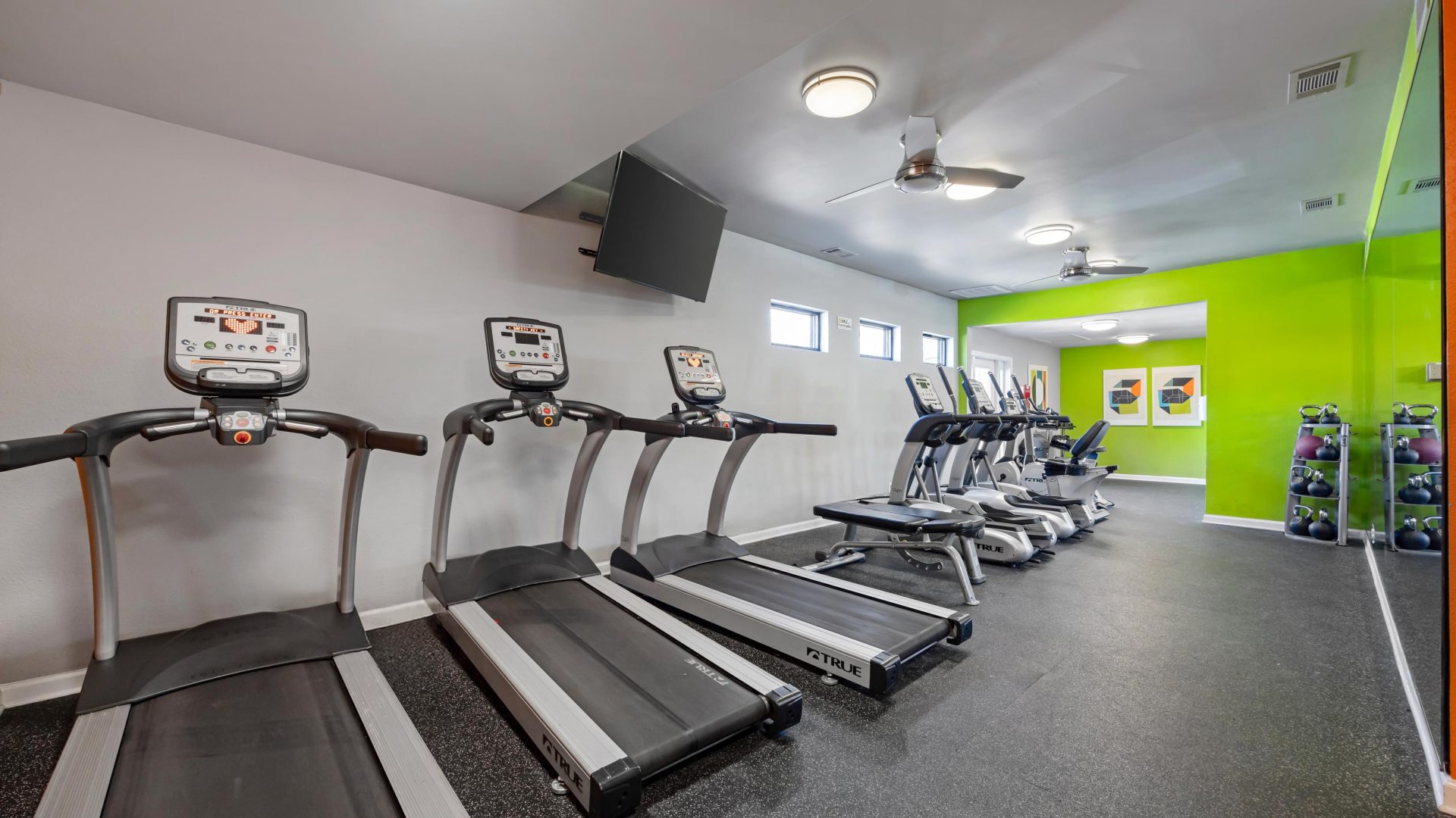 a gym room with tread machines and green walls at The  Landry